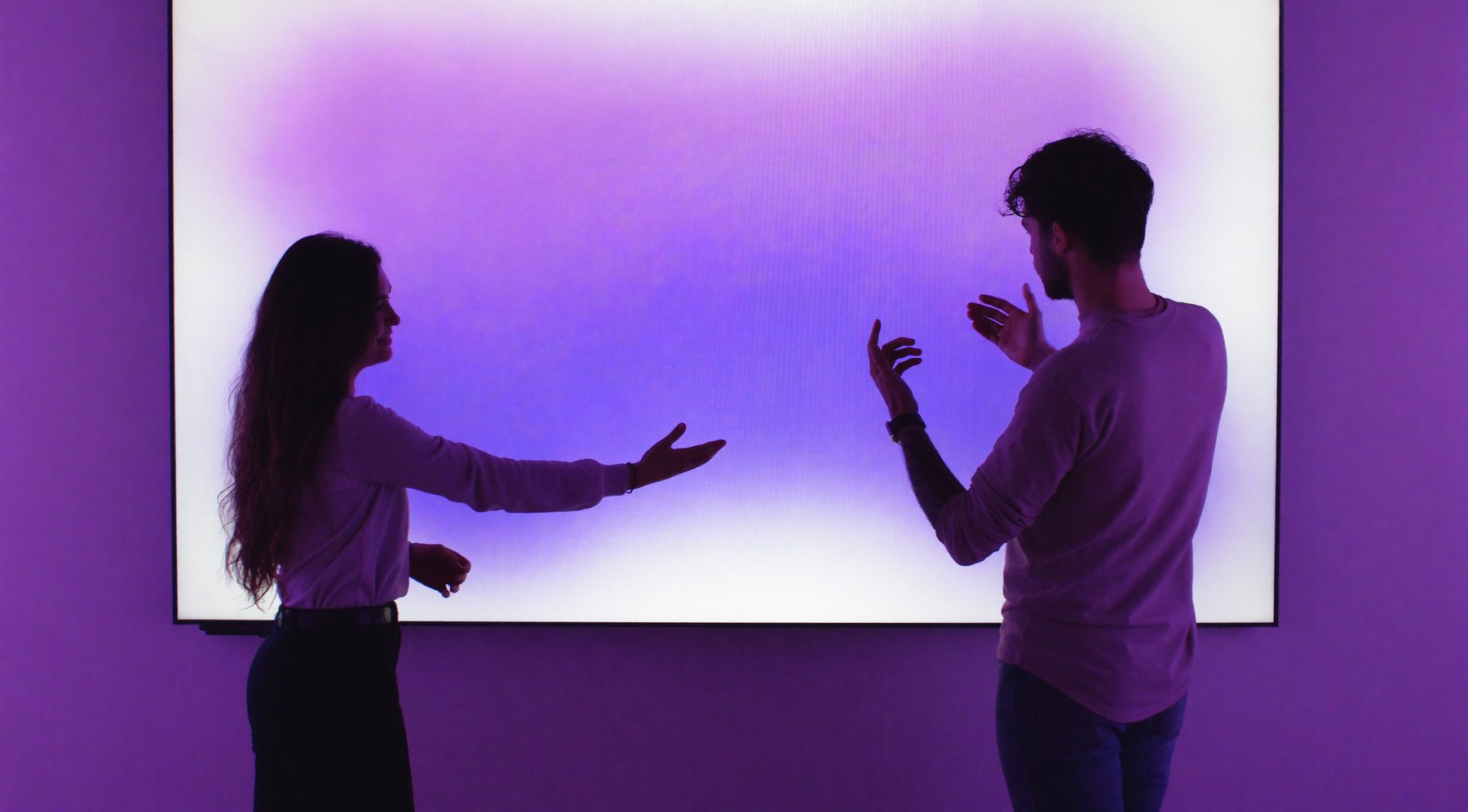 Two people working at a large glowing screen